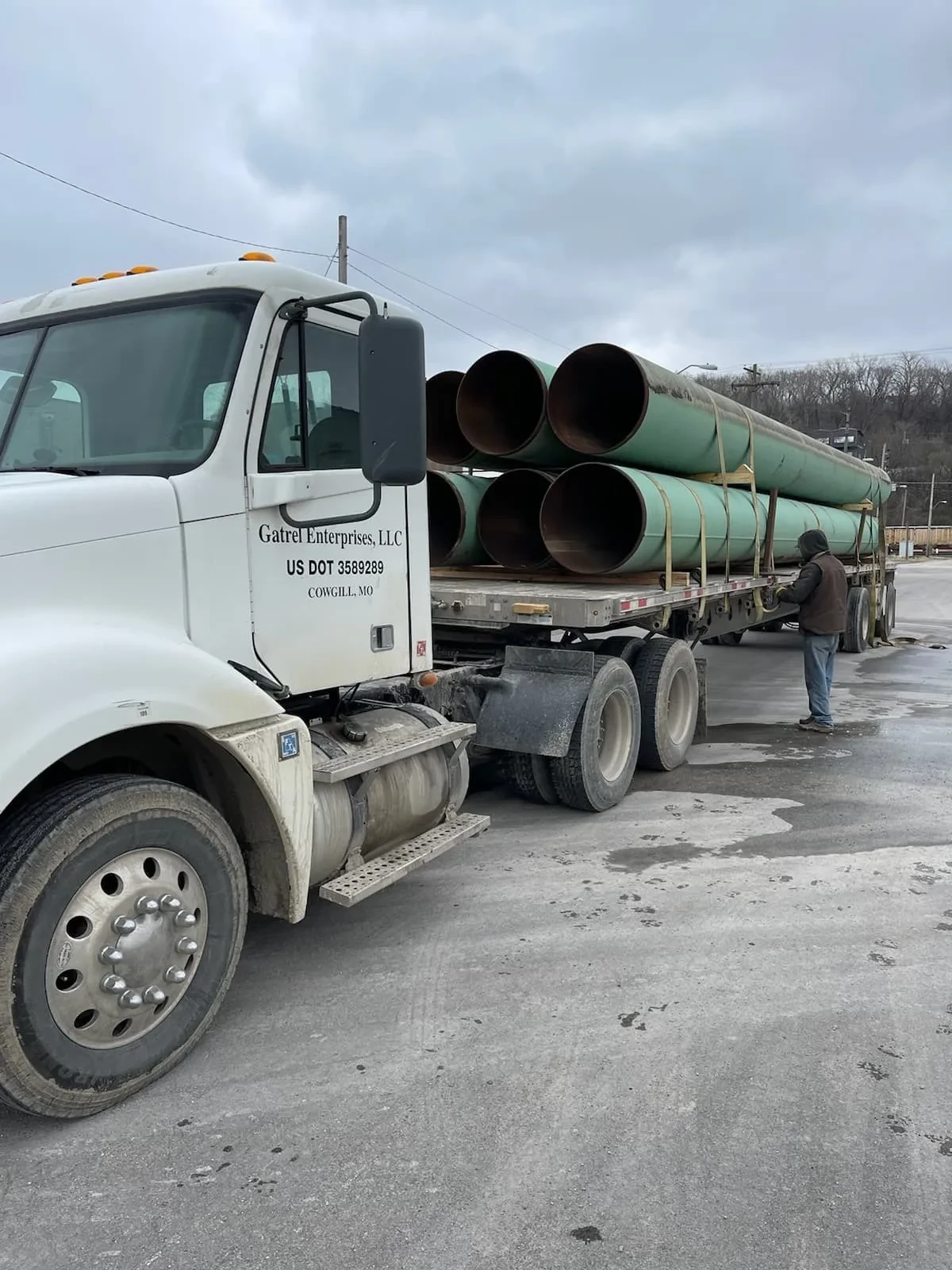 Gatrel Enterprises truck hauling large green steel pipes